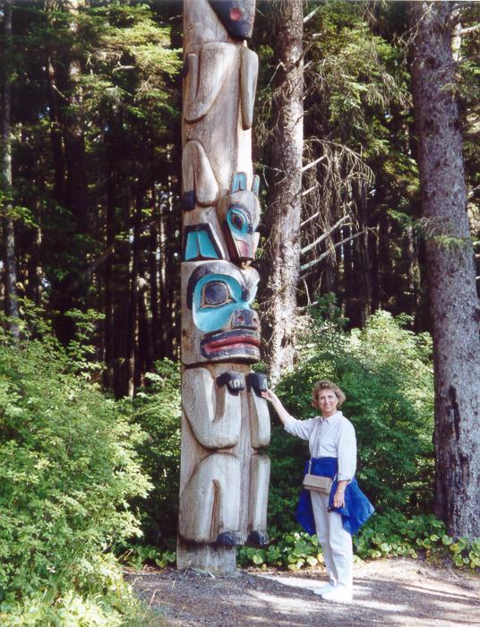 Photo of Lynda Plymate standing in front of totem pole, Sitka, Alaska