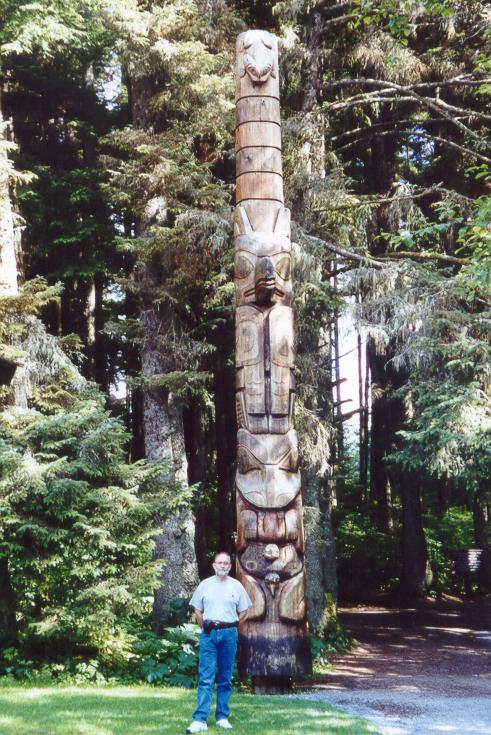 Photo of Tom Plymate standing in front of totem pole, Sitka, Alaska